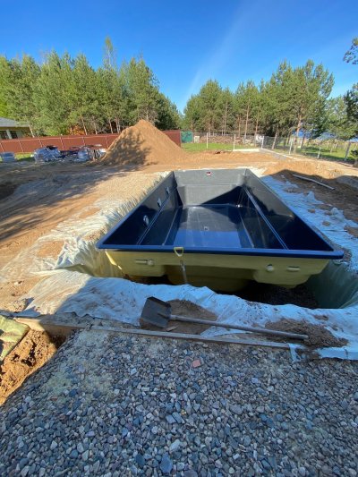 Композитный бассейн с темной чашей в котловане на строительной площадке